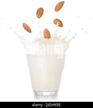 mandorle che cadono in uno spruzzo di vetro di latte isolato su sfondo bianco Foto Stock