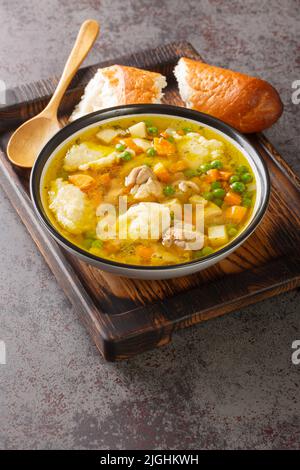 Brodo di pollo con verdure e gnocchi da vicino in una ciotola sul tavolo. Verticale Foto Stock