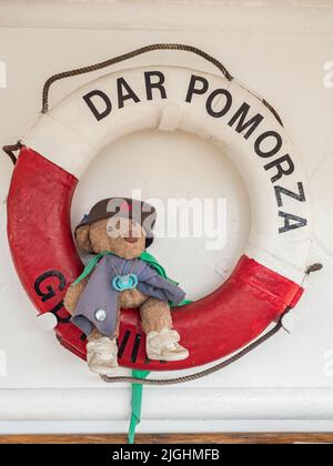 Gdynia, Polonia - Maggio 2019: Lifebuoy nei colori della bandiera polacca e un orsacchiotto sul veliero polacco Dar Pomorza - attualmente un mu Foto Stock