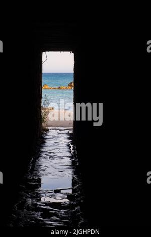 Vista pomeridiana attraverso l'apertura di un sottopassaggio delle rocce e della spiaggia intorno a Petra tou Romiou, a Paphos, Cipro. È considerato come Afrodite' Foto Stock