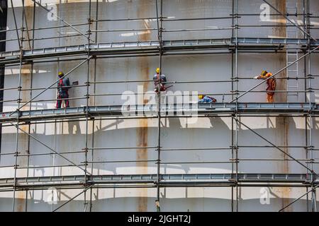 Cantiere lavoratori maschi serbatoio olio installazione ponteggi in raffineria sito Foto Stock