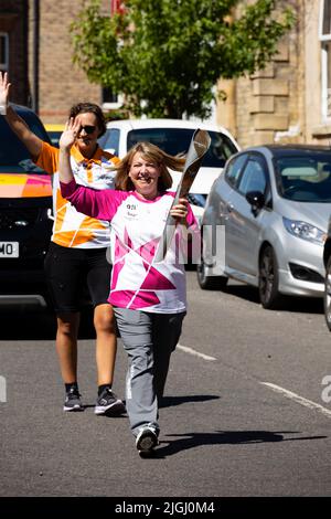 Lyndsey Young, il fondatore della panchina, porta il Queens Baton lungo Avenue Road, Grantham, Lincolnshire, Inghilterra. Il Baton è sulla strada per la 16 Foto Stock