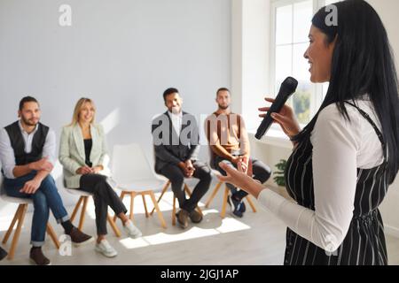 Una donna sorridente parla di formazione con i dipendenti Foto Stock