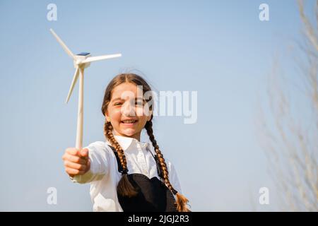 Il bambino gioca e guarda interessato a un giocattolo a turbina eolica - concetto di generazione futura e Enewable Energy Foto Stock