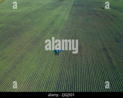 Un trattore erpita un campo verde. Vista aerea dell'aratura del trattore agricolo sul campo. Trattore che prepara in primavera il coltivatore a base di terreno Foto Stock