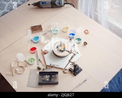Concetto di stile di vita, lavoro da casa per reinventare la vostra vita - Jewelry designer workplace. Creazione di strumenti per gioielli. Tecnica di produzione di smalto minankari georgiano. Gioielliere che fa gli accessori in officina. Foto Stock