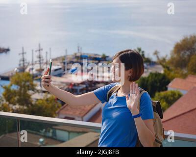 Viaggio in Turchia, città vecchia Antalya Kaleci. Felice turista asiatico con zaino passeggiate nella città vecchia. Donna in cerca della città vecchia e il porto dal punto di vista scatta foto selfie Foto Stock