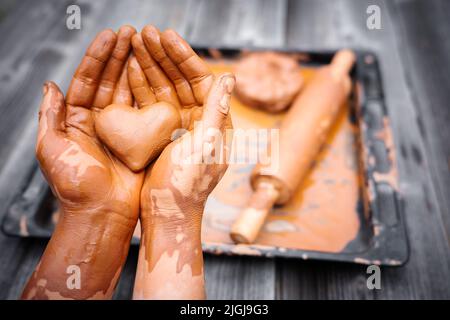 Cuore fatto di argilla del vasaio nelle mani di un vasaio maestro. Concetto di amore Foto Stock