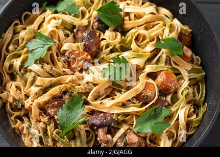 Fettuccini o alfredo fatti in casa, detti anche Funghi Porcini cotti in una padella in ghisa con funghi e salsa cremosa Foto Stock