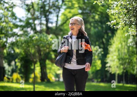 Felice donna elegante sorridente e guardando fiducioso Foto Stock