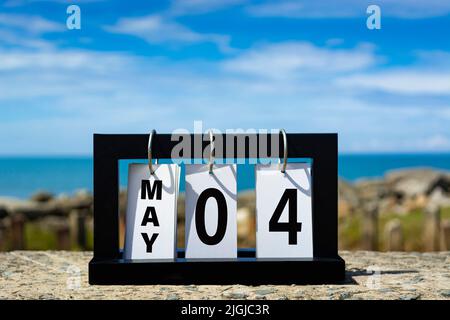 Maggio 04 calendario data testo su cornice di legno con sfondo sfocato di oceano. Informazioni sulla data del calendario. Foto Stock