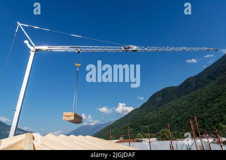 Gru da cantiere con carico appeso di asse in legno su un cielo blu Foto Stock