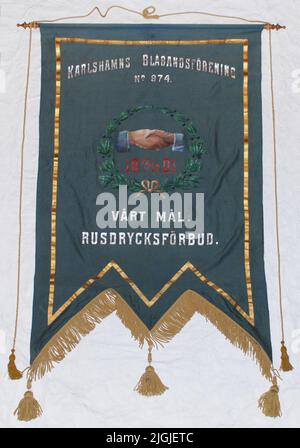 Stand Fana, banner. Doppia armatura, con fondo a tre zeri, dotata di ciglia e nappine gialle. Lana intrecciata satinata, blu-grigia con decorazioni dipinte. Telaio in oro. Testo in Argento 'Karlshamns Blåbandförening No 974.', 'il nostro obiettivo: Bevanda di rush.' Nel mezzo stretta di mano all'interno della corona e data in rosso '19 12/12 01'. D'altra parte, in parte lo stesso, ma con angelo e stella. Montato su pinze in legno. Acquistato 1986-10-21 da Karlskrona Second Hand, Drottninggatan/Alamedan, Karlskrona, attraverso Torsten Samzelius, Karlskrona. Foto Stock