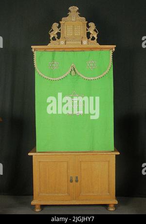 Toraskåp Torac armadi di quercia con 2 paia di porte. Parte superiore più stretta. Segni chiave in ottone con anelli ovali. Il cabinet si trova su quattro piedini girati. Sulla parte anteriore della corona del mobile, due aste di ottone sono sedute per il perdono. Il gabinetto ha un pezzo superiore di scolpito nel centro di quercia vi sono le tavole di pietra di Mosè, in aggiunta uno scudo coronato con il dio di Dio circondato da fogliame e angeli. Sotto le "tavolette a tono" ci sono i fogli con Girlander e testo ebraico, dove all'esterno ci sono due leoni spostati. L'altezza della parte superiore è di 485 mm, la larghezza di 600 mm e la profondità di 45 mm. Da Foto Stock