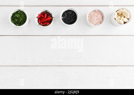 Varietà di condimento alimentare su sfondo bianco di legno Foto Stock