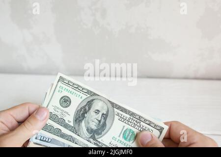 Mano maschile che contiene cento banconote da dollaro Foto Stock