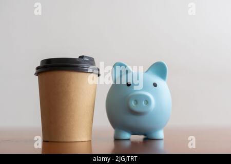 Tazza di caffè artigianale levitating con biggy bank su sfondo blu. Foto Stock