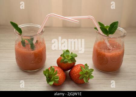 Due frullati di fragole in un bicchiere con cannucce Foto Stock