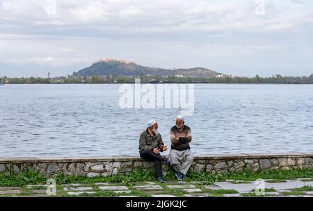 Srinagar, India. 24th Mar 2022. I vecchi parlano su una riva del lago dal durante una serata nuvolosa a Srinagar. (Credit Image: © Idrees Abbas/SOPA Images via ZUMA Press Wire) Foto Stock