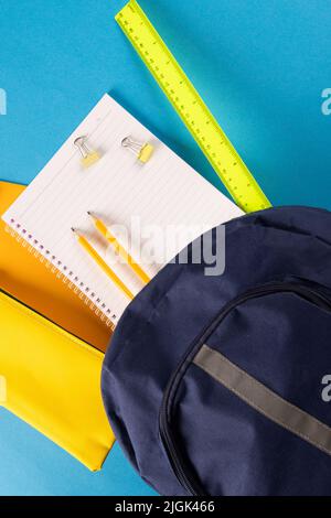 Immagine di forniture scolastiche, notebook, zaino, righello, graffette su sfondo blu Foto Stock