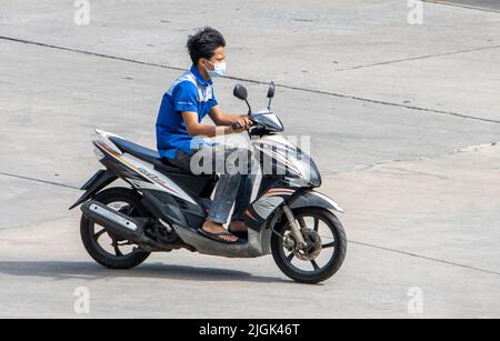 SAMUT PRAKAN, THAILANDIA, MAR 29 2022, un uomo con maschera di faccia corre una moto Foto Stock