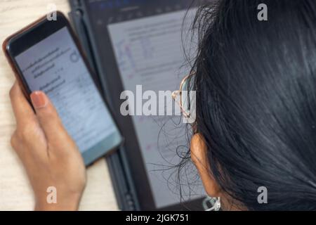 Giovane donna guarda su un display di dispositivi elettronici, vista dall'alto Foto Stock