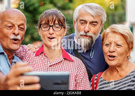 Coppie anziane che prendono selfie con smartphone - riunione degli amici anziani divertirsi all'aperto con gli altri Foto Stock