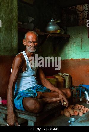 Kolkata, India - 9 luglio 2022: Un uomo anziano che vende il tè in un piccolo spazio confinato sulla strada. Messa a fuoco selettiva sul volto. Foto Stock