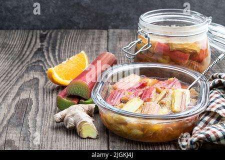 Stufato di rabarbaro fatto in casa in una ciotola di vetro su un tavolo di legno Foto Stock