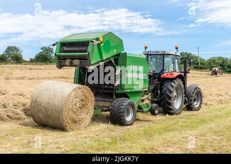 Drinagh, West Cork, Irlanda. 11th luglio 2022. Il contadino George Wilson trasforma il fieno per essere salvato con un Massey Ferguson 168 del 1978 utilizzando un fieno in una giornata calda e umida a West Cork. Suo figlio, Evan, galla il fieno. Credit: AG News/Alamy Live News Foto Stock