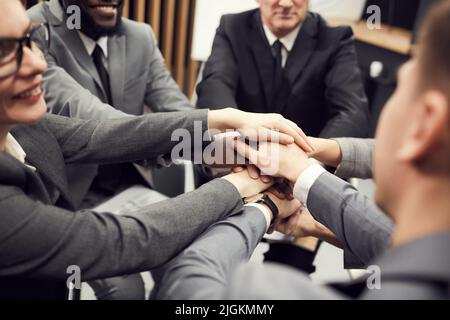 Primo piano di un solido team di professionisti aziendali che si trovano in cerchio e si accatastano le mani come simbolo di unità al corso di formazione per l'azienda Foto Stock