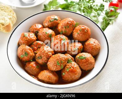 Vista ravvicinata delle polpette con salsa di pomodoro nel recipiente su sfondo bianco. Foto Stock