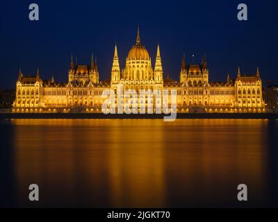 Edificio del Parlamento a Budapest, Ungheria. Parlamento e riflessioni sul Danubio. Illuminazione serale dell'edificio con acqua sottostante Foto Stock