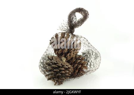 Vacanze decorazione coni di pino in sacchetto di rete isolato su sfondo bianco Foto Stock