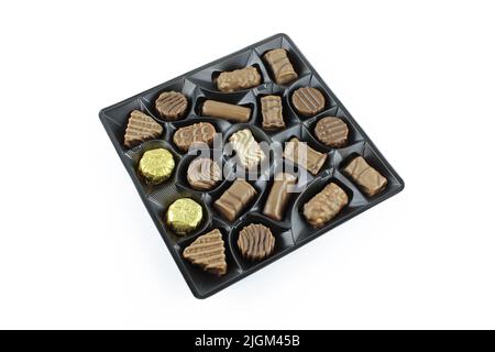 Varietà di praline al cioccolato dolce in confezioni di plastica isolate su fondo bianco Foto Stock