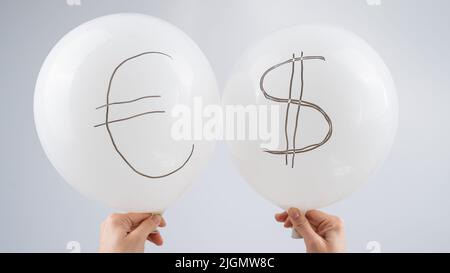 Donna che tiene due palloncini bianchi con simbolo del dollaro e dell'euro. Foto Stock