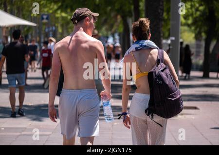 Barcellona, Spagna. 11th luglio 2022. I turisti sono visti sul molo di Barceloneta dirigendosi verso la spiaggia indossando il beachwear. Seconda ondata di calore estremo che può superare i 44 gradi Celsius in alcune regioni della Spagna. La Catalogna, attualmente al livello uno e dopo settimane di accumulo di alte temperature e di poca pioggia, soffrirà questa settimana alcuni giorni di temperature al di sopra di quanto è solito per queste date Credit: SOPA Images Limited/Alamy Live News Foto Stock