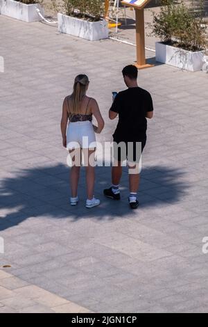 Barcellona, Spagna. 11th luglio 2022. Una coppia turistica è visto consultare il loro dispositivo mobile sotto l'ombra di una palma sulla spiaggia di Sant Sebantian. Seconda ondata di calore estremo che può superare i 44 gradi Celsius in alcune regioni della Spagna. La Catalogna, attualmente al livello uno e dopo settimane di accumulo di alte temperature e di poca pioggia, soffrirà questa settimana alcuni giorni di temperature al di sopra di quanto è solito per queste date (Foto di Paco Freire/SOPA Images/Sipa USA) Credit: Sipa USA/Alamy Live News Foto Stock