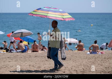Barcellona, Spagna. 11th luglio 2022. Un venditore di ombrelloni è visto sulla spiaggia a Barceloneta seconda ondata di calore estremo che può superare i 44 gradi Celsius in alcune regioni della Spagna. La Catalogna, attualmente al livello uno e dopo settimane di accumulo di alte temperature e di poca pioggia, soffrirà questa settimana alcuni giorni di temperature al di sopra di quanto è solito per queste date (Foto di Paco Freire/SOPA Images/Sipa USA) Credit: Sipa USA/Alamy Live News Foto Stock