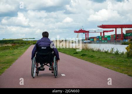 Tilburg, Paesi Bassi. Femmina di sclerosi multipla che si occupano del paziente con la sua condizione di on e off mediante una sedia a rotelle per ottenere lungo. Foto Stock