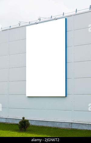 Modello di simulazione. Grande cartello bianco verticale, cartellone pubblicitario su una moderna parete esterna Foto Stock