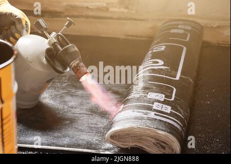 installazione del rivestimento impermeabilizzante sul pavimento con cannello e resina, lavori di riparazione a casa. Foto Stock