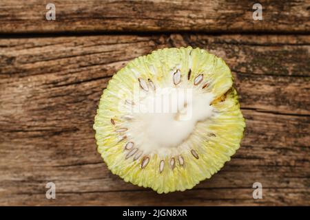 Metà dell'arancio di osage fresco su piatto di legno Foto Stock