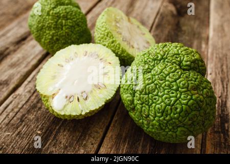 Arancio di osage pieno e mezzo su tavola di legno Foto Stock