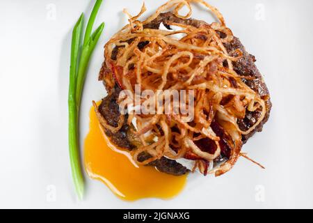 Anelli di cipolla fritti su piatto di cotoletta di carne Foto Stock