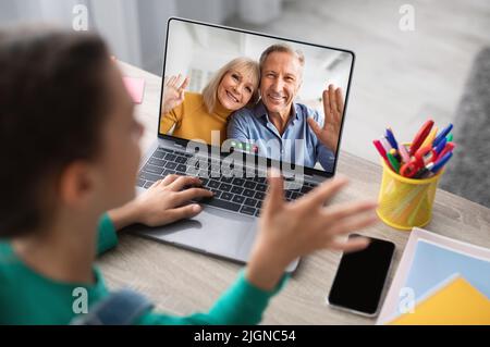 Little Girl effettua una videochiamata ai nonni tramite il portatile a casa Foto Stock