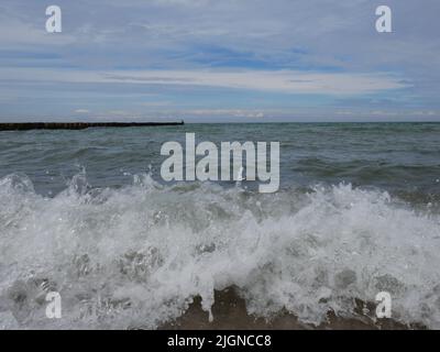 Un'onda di rottura / spruzzi in una spiaggia del Mar Baltico Foto Stock