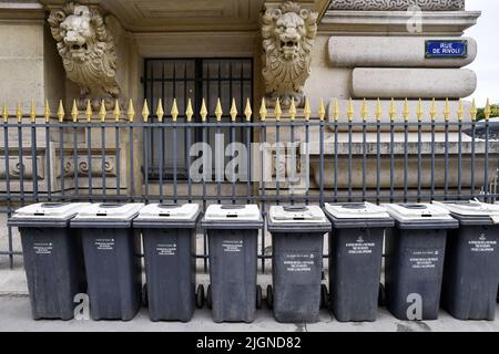 una fila di bidoni della spazzatura comunali standard grigi e bianchi allineati su un marciapiede lungo Rue de Rivoli a Parigi, Francia Foto Stock