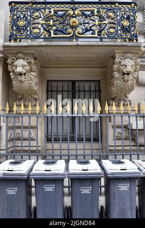 una fila di bidoni della spazzatura comunali standard grigi e bianchi allineati su un marciapiede lungo Rue de Rivoli a Parigi, Francia Foto Stock