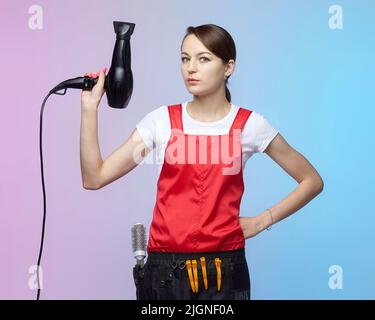 la ragazza del parrucchiere tiene un asciugacapelli nelle sue mani. scatto della foto nello studio Foto Stock